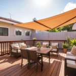 A sunlit patio with wooden deck, cushioned seating, awning, and plants, illustrating a durable outdoor seating area.